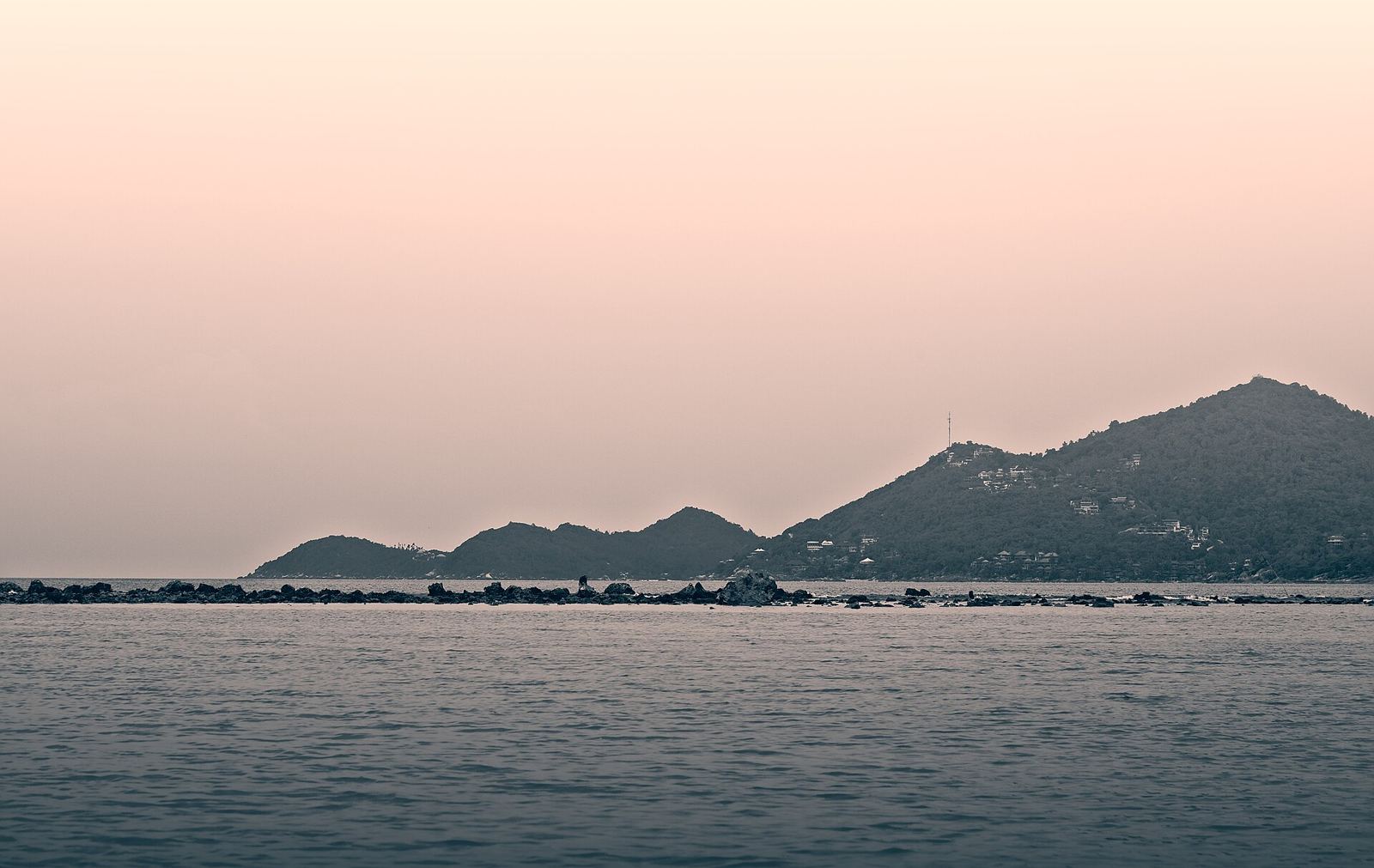 Calm sea and a rocky, wooded headland at dusk seen from Chaweng Beach, Koh Samui